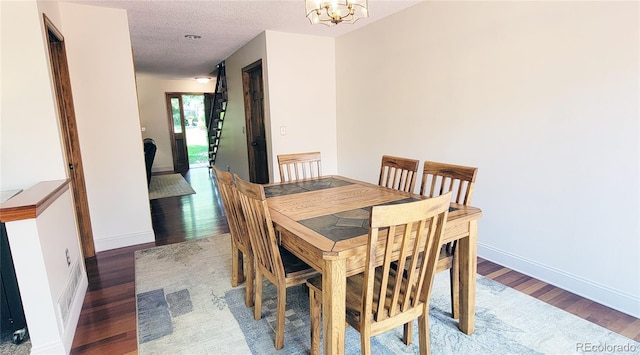 dining space featuring a textured ceiling, dark hardwood / wood-style flooring, and an inviting chandelier