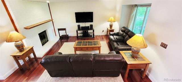 living room with wood-type flooring and a brick fireplace