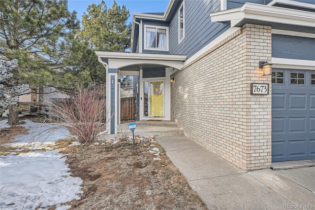 snow covered property entrance featuring a garage