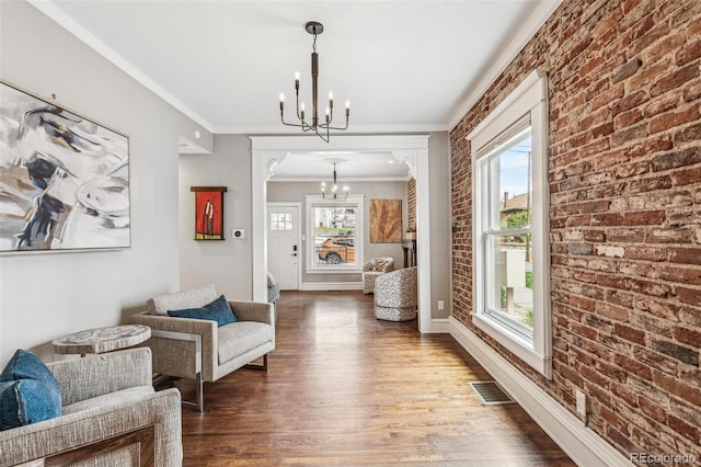 living area with an inviting chandelier, ornamental molding, visible vents, wood finished floors, and arched walkways