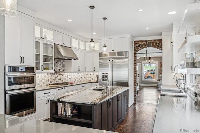 kitchen with open shelves, under cabinet range hood, white cabinets, a sink, and appliances with stainless steel finishes
