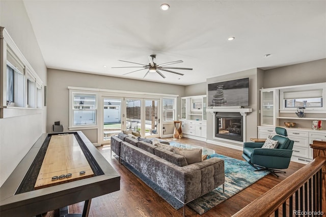 living area featuring a glass covered fireplace, recessed lighting, a ceiling fan, and dark wood finished floors