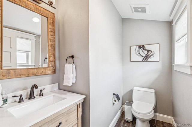 bathroom with toilet, baseboards, visible vents, and plenty of natural light