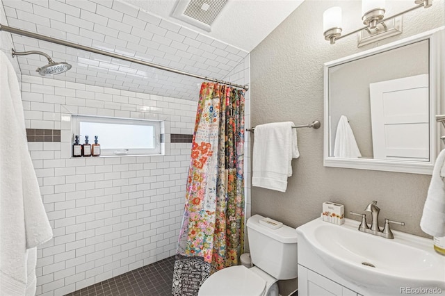 full bath with toilet, visible vents, a tile shower, and vanity