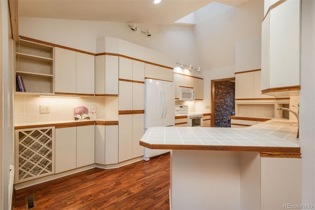 kitchen with tile countertops, white appliances, a peninsula, visible vents, and backsplash