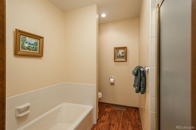 bathroom featuring visible vents, toilet, an enclosed shower, wood finished floors, and a garden tub