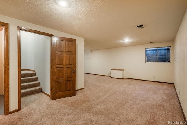 finished below grade area featuring visible vents, baseboards, carpet flooring, and stairs