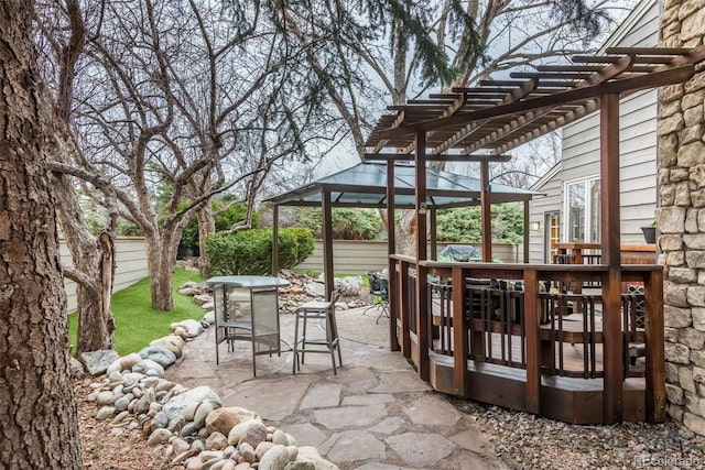 view of patio with a wooden deck, outdoor dining space, a pergola, and fence