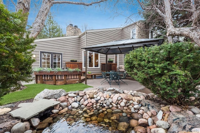 back of house with a gazebo, a wooden deck, and a chimney