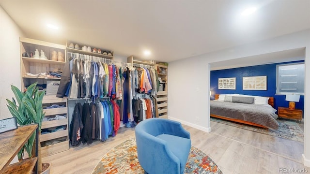 walk in closet with light hardwood / wood-style flooring