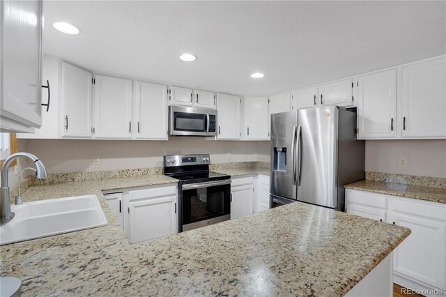 5603 S Pagosa Ct, Centennial, CO 80015 - kitchen featuring a peninsula, recessed lighting, white cabinets, a sink, and stainless steel appliances