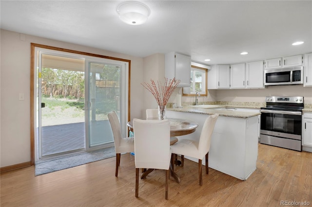 5603 S Pagosa Ct, Centennial, CO 80015 - kitchen featuring a peninsula, light stone countertops, a sink, light wood-style flooring, and appliances with stainless steel finishes