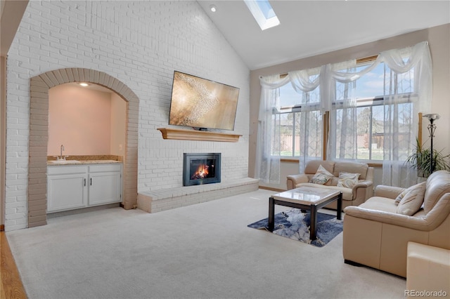 5603 S Pagosa Ct, Centennial, CO 80015 - living room featuring light colored carpet, a fireplace, high vaulted ceiling, a skylight, and bar area