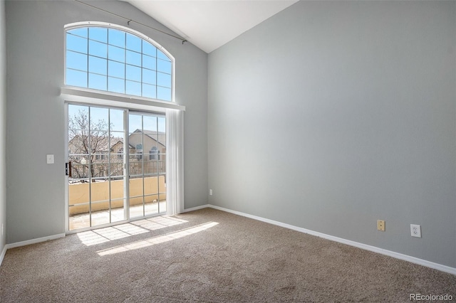 carpeted empty room with baseboards and high vaulted ceiling