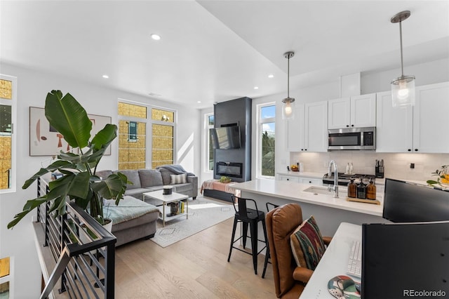 1232 N Yates St Unit 3, Denver, CO 80204 - kitchen featuring stainless steel microwave, light wood-type flooring, a breakfast bar area, backsplash, and hanging light fixtures