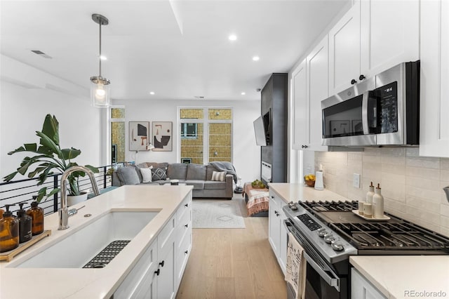 1232 N Yates St Unit 3, Denver, CO 80204 - kitchen featuring stainless steel appliances, light wood-style flooring, decorative backsplash, light countertops, and white cabinetry