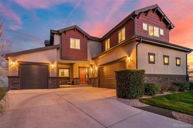 view of front of home with concrete driveway, an attached garage, stone siding, and stucco siding