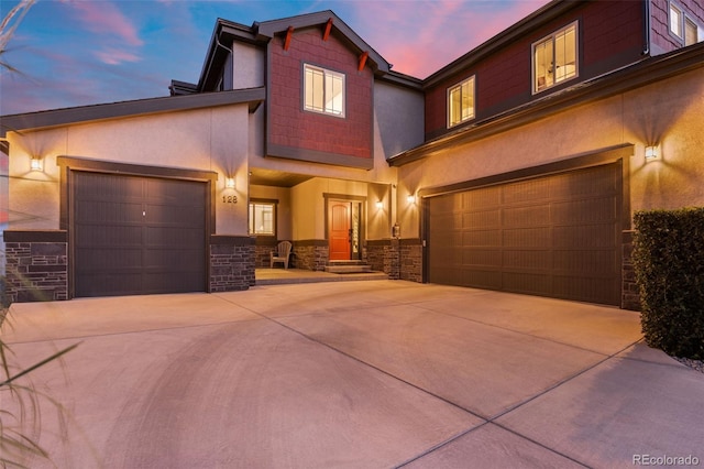 view of front facade featuring an attached garage, concrete driveway, stone siding, and stucco siding