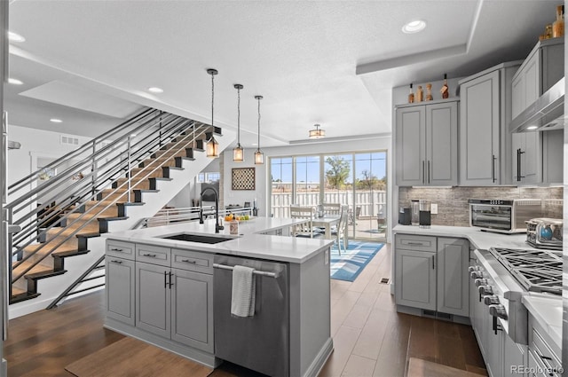 kitchen with backsplash, gray cabinetry, stainless steel appliances, and a sink