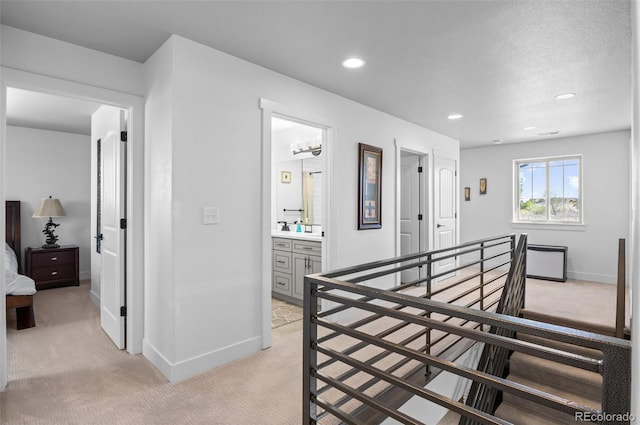 corridor featuring recessed lighting, an upstairs landing, baseboards, and light carpet