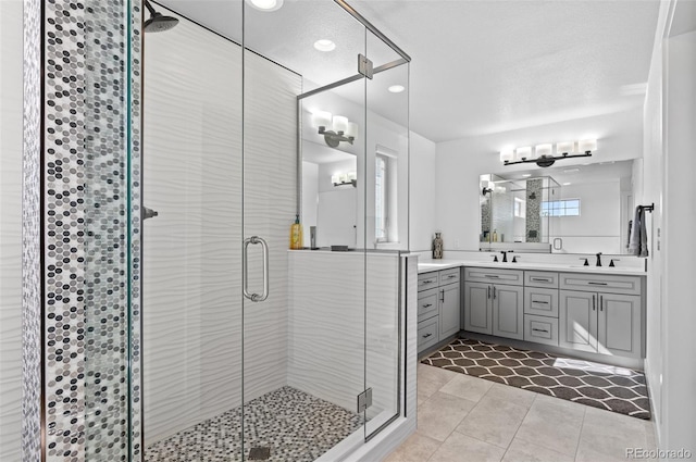 full bath with a sink, a stall shower, double vanity, and tile patterned floors