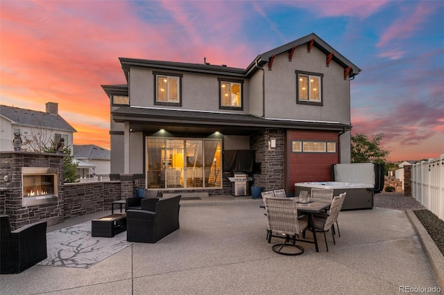 back of property featuring stucco siding, an outdoor living space with a fireplace, stone siding, a patio, and a fenced backyard