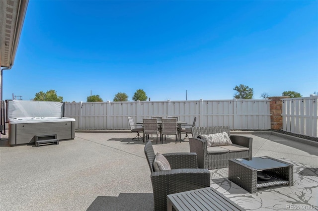 view of patio featuring outdoor dining space, fence, and a hot tub