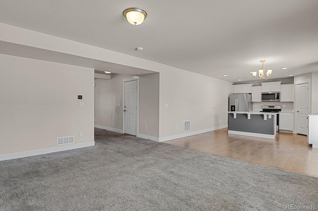 unfurnished living room with light carpet and an inviting chandelier