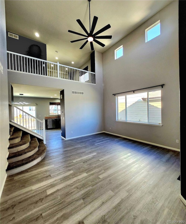 unfurnished living room featuring wood finished floors, a ceiling fan, visible vents, and baseboards