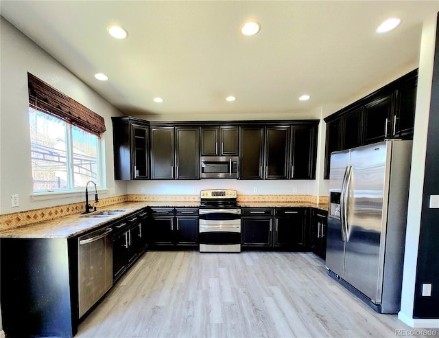 kitchen with a sink, recessed lighting, light wood-type flooring, and stainless steel appliances