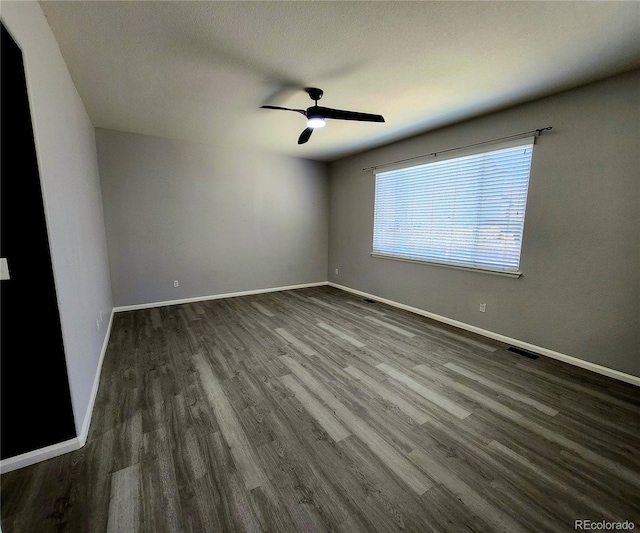 unfurnished room with dark wood-style floors, baseboards, and ceiling fan