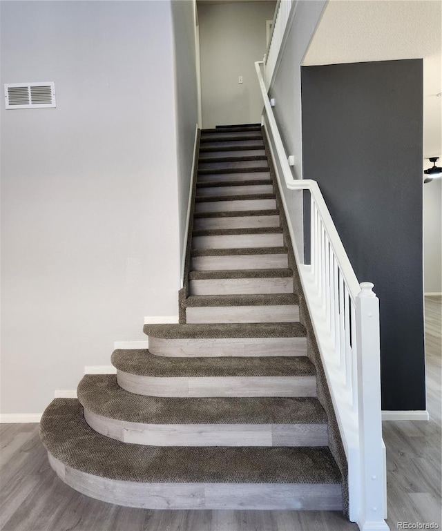 stairs featuring wood finished floors, visible vents, and baseboards