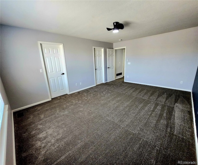 unfurnished bedroom with dark colored carpet and baseboards