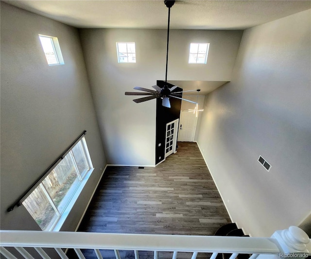 unfurnished living room featuring plenty of natural light, wood finished floors, and a ceiling fan