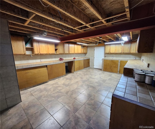 kitchen featuring open shelves, decorative backsplash, and tile counters