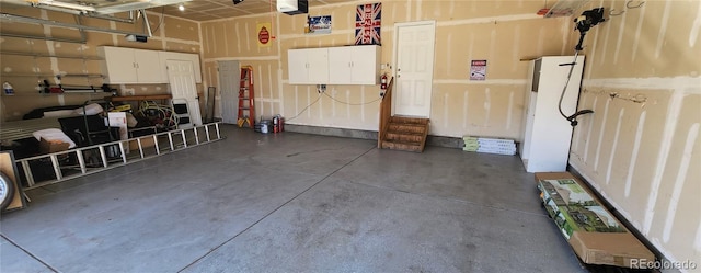 garage with a garage door opener and freestanding refrigerator