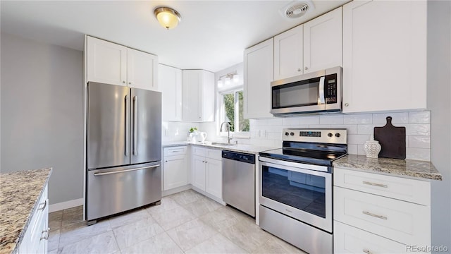 kitchen featuring backsplash, white cabinetry, light stone countertops, sink, and stainless steel appliances