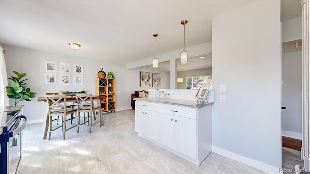 kitchen with light stone counters, electric range, decorative light fixtures, and white cabinets