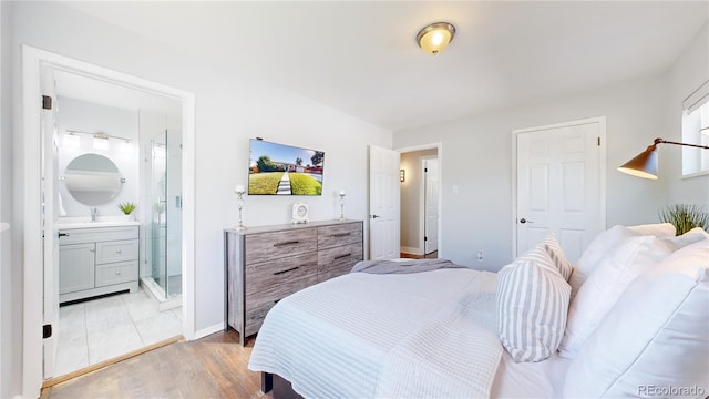 bedroom featuring light hardwood / wood-style floors, ensuite bathroom, and sink