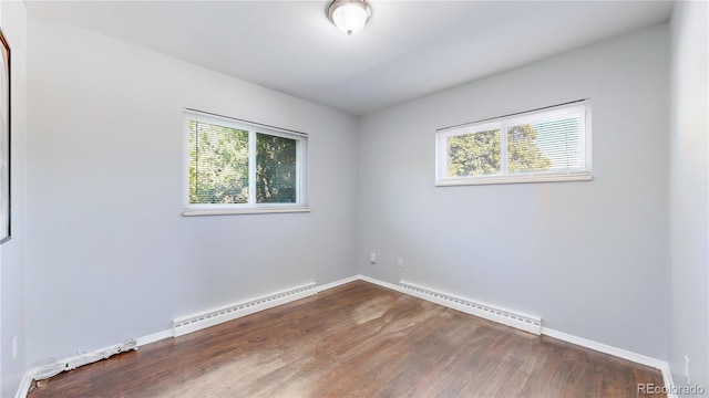 empty room with dark hardwood / wood-style floors, a baseboard radiator, and a wealth of natural light