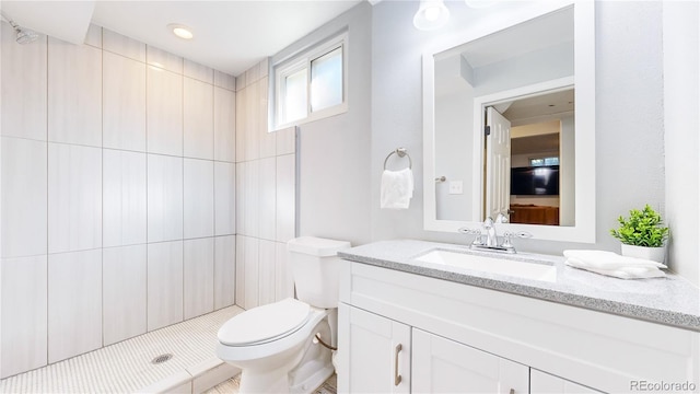 bathroom with vanity, a tile shower, and toilet