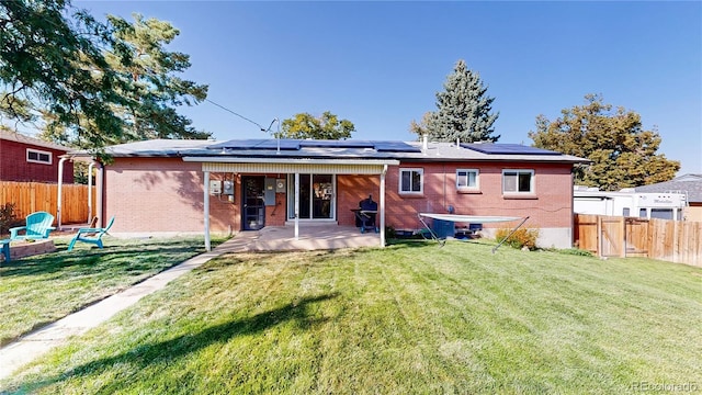 back of property with a patio area, solar panels, and a yard