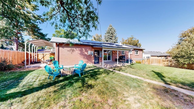 back of house featuring an outdoor fire pit, a patio, and a lawn