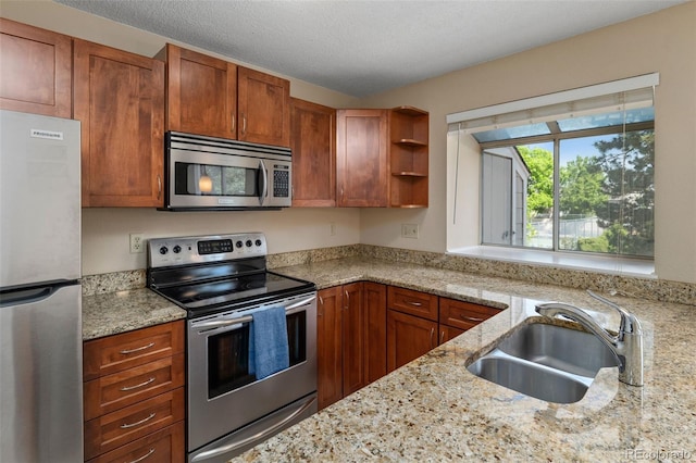 18171 E Arizona Ave Unit B, Aurora, CO 80017 - kitchen with stainless steel appliances, a sink, open shelves, light stone countertops, and brown cabinetry