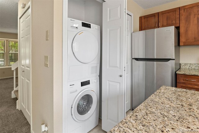 18171 E Arizona Ave Unit B, Aurora, CO 80017 - laundry room with stacked washing machine and dryer, a textured ceiling, and light colored carpet