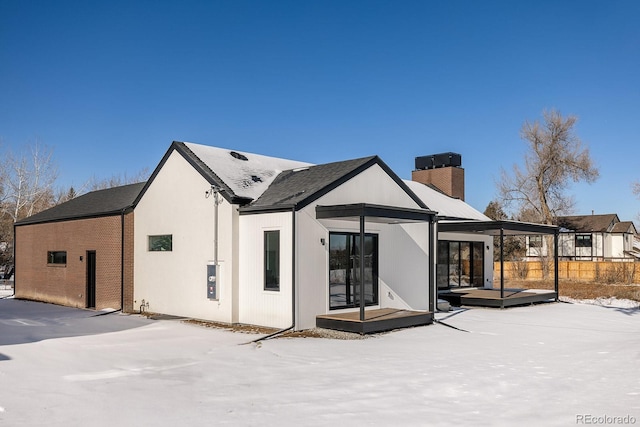 snow covered rear of property featuring a deck