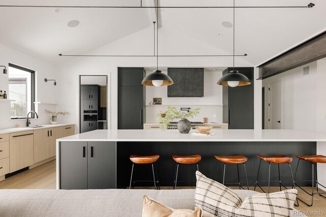 kitchen with a breakfast bar area, light hardwood / wood-style flooring, dishwashing machine, a kitchen island, and pendant lighting