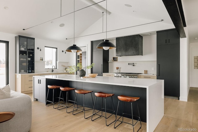 kitchen with a spacious island, stainless steel gas stovetop, hanging light fixtures, and light wood-type flooring