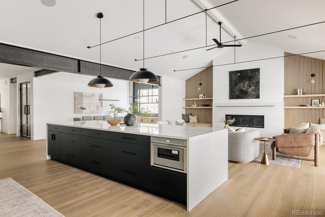 kitchen featuring pendant lighting, oven, light hardwood / wood-style flooring, and vaulted ceiling with beams