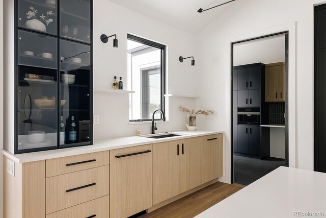 kitchen with light brown cabinetry, sink, and hardwood / wood-style flooring